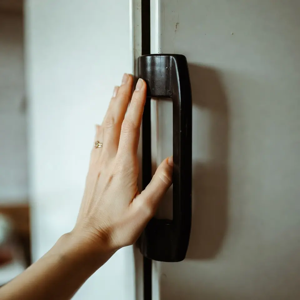 A woman touches the hot wall of a refrigerator